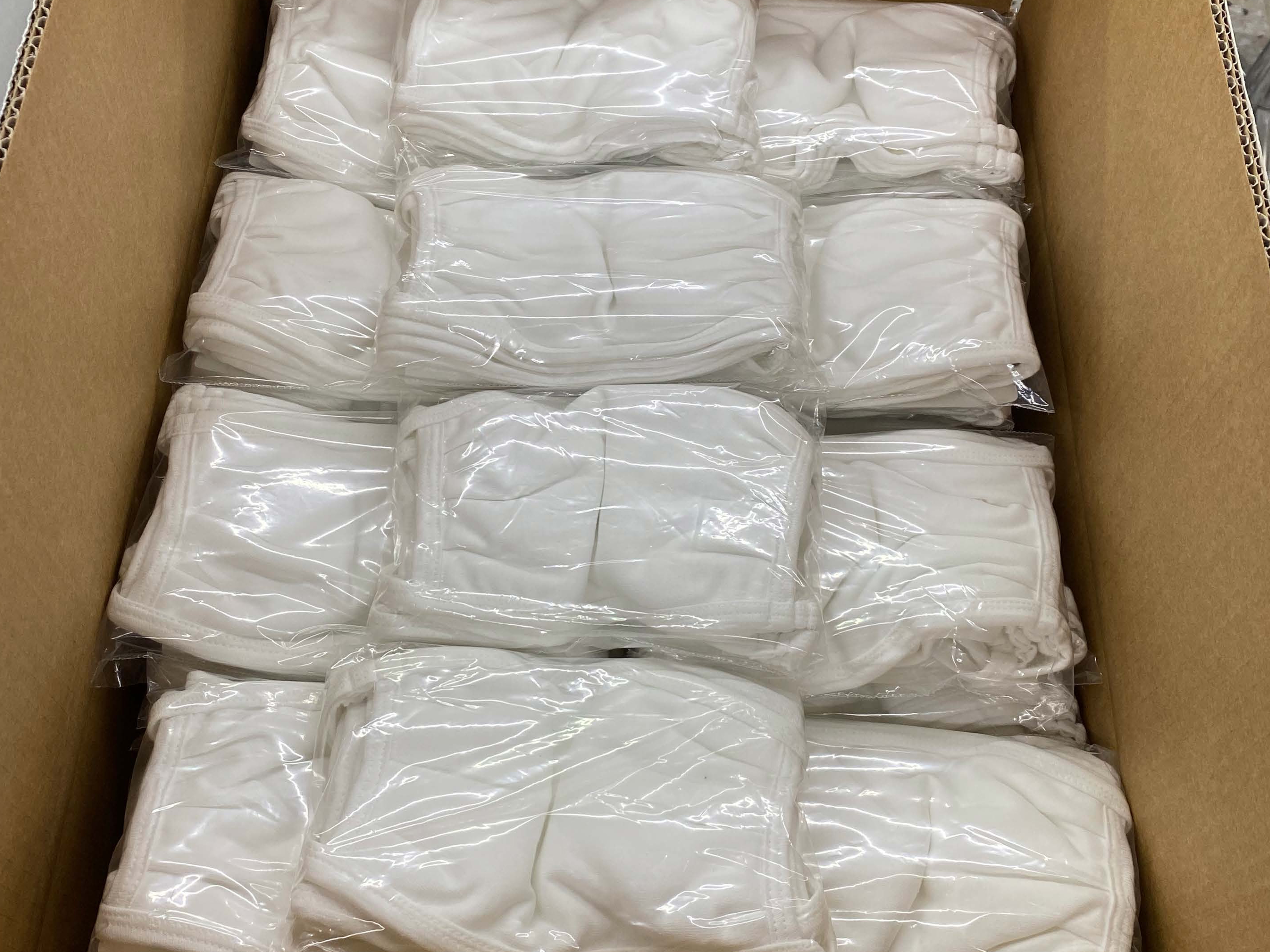 Bundles of cloth face masks are packaged and placed into boxes for shipment.
